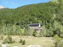 A l´altra banda hi destaca un bosc frondós i l´edifici del Parador del Monte Perdido.